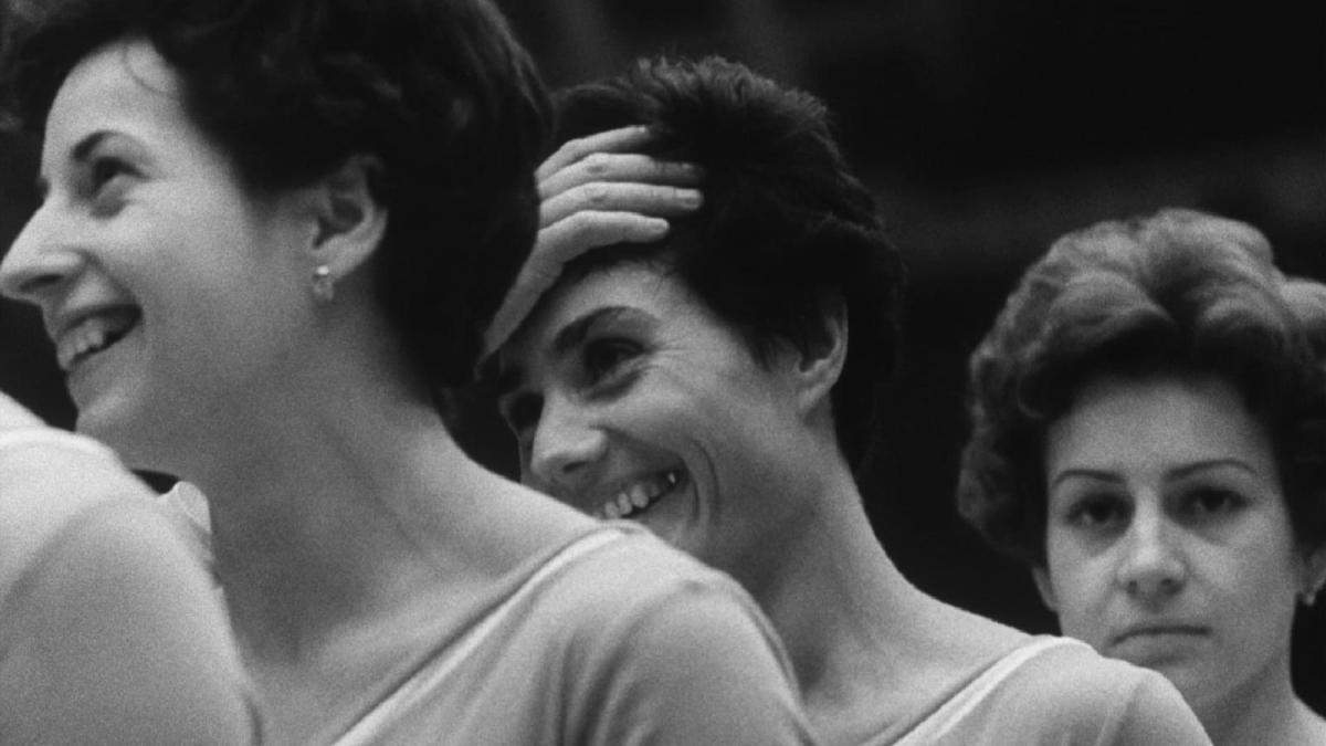 three woman standing in a row with woman in middle's hand on head
