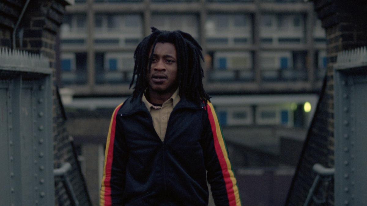 black man with dreads walking through city 