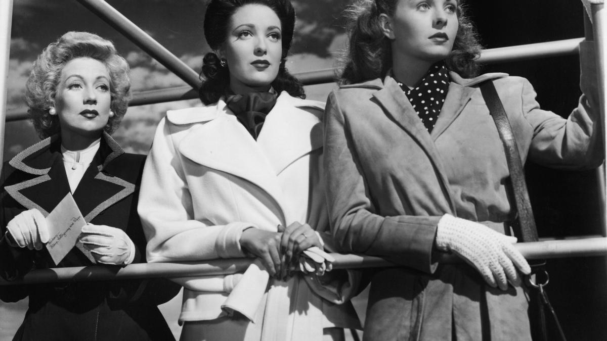 three woman standing on boat railing looking in distance