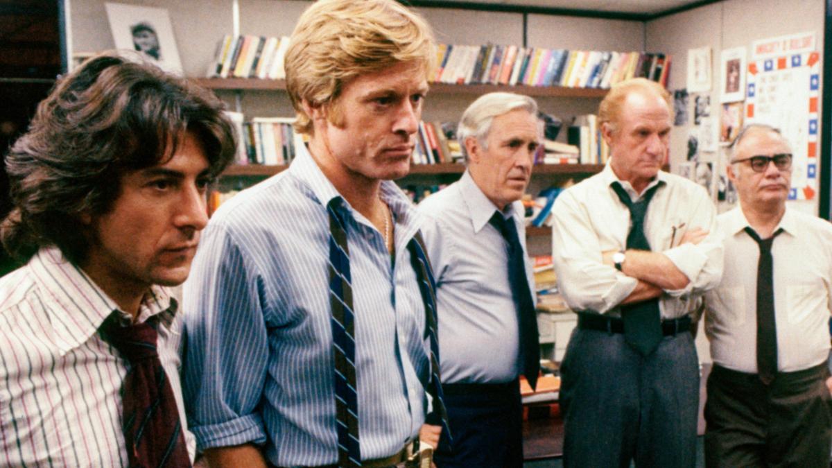 men in newsroom gathered around