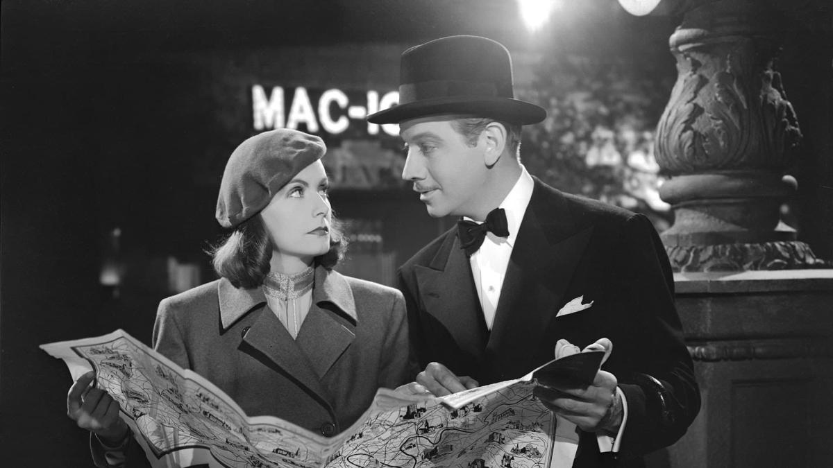 man and woman standing outside in coats and hat looking at a map
