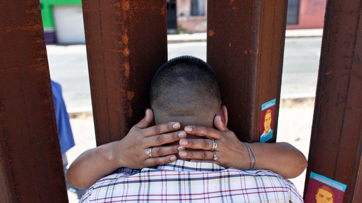 man being hugged through fence