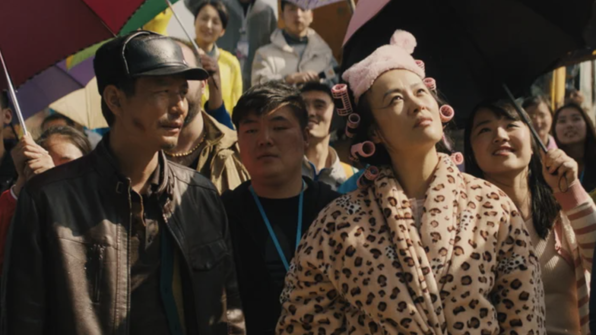 three people in large crowd looking towards sky 