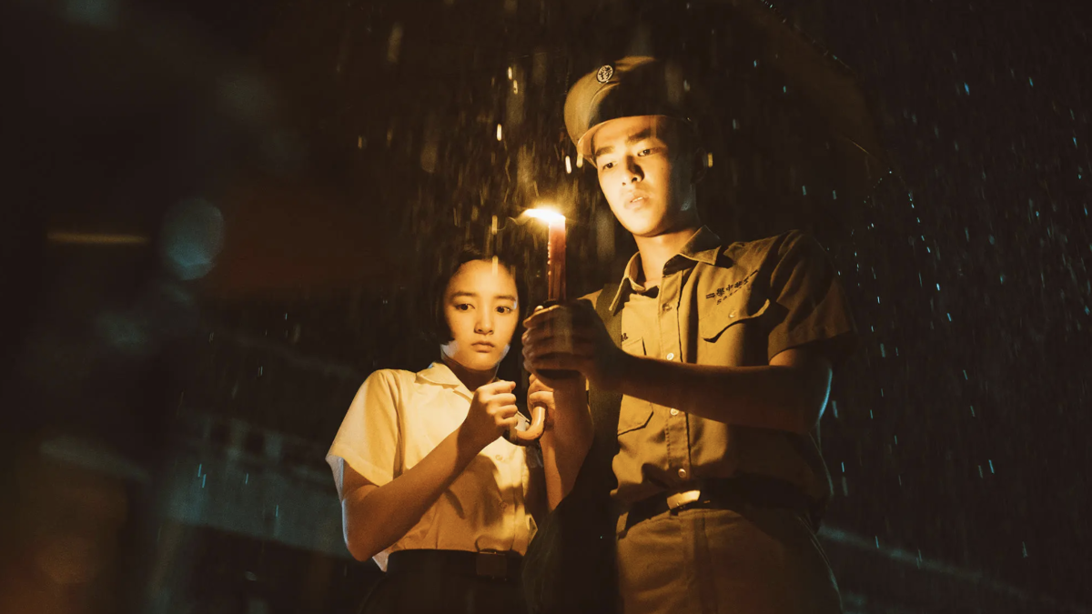 boy in military uniform holidng a cnadle light and girl standing behind him