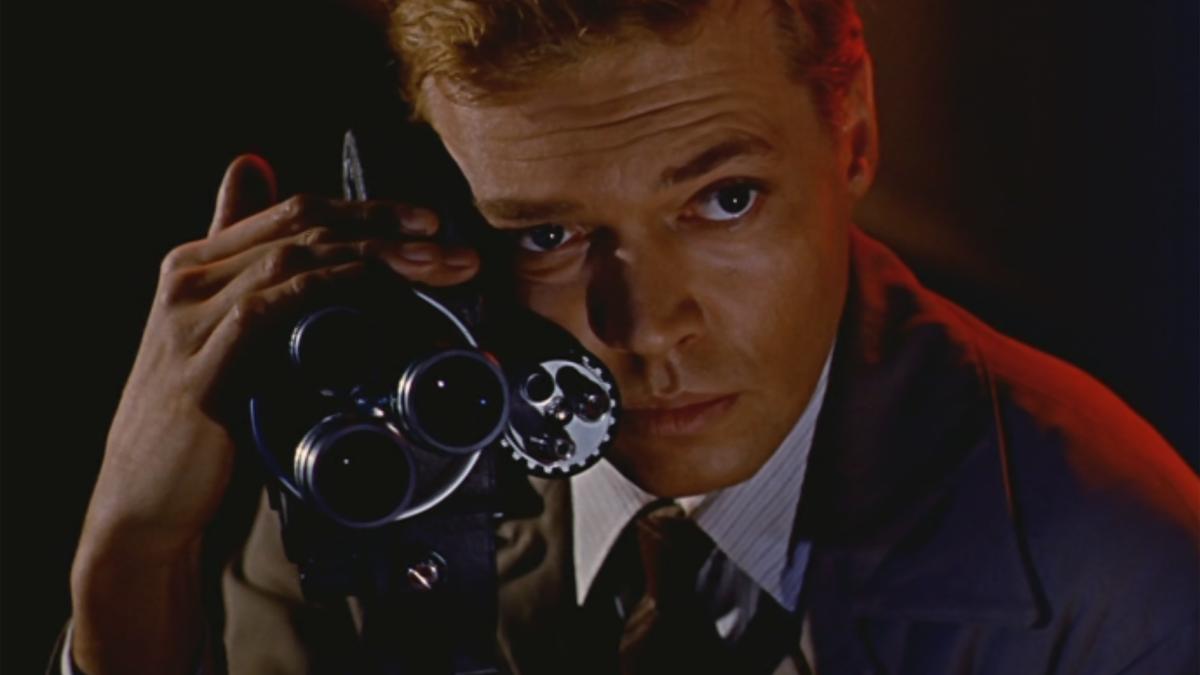 man peering through film camera