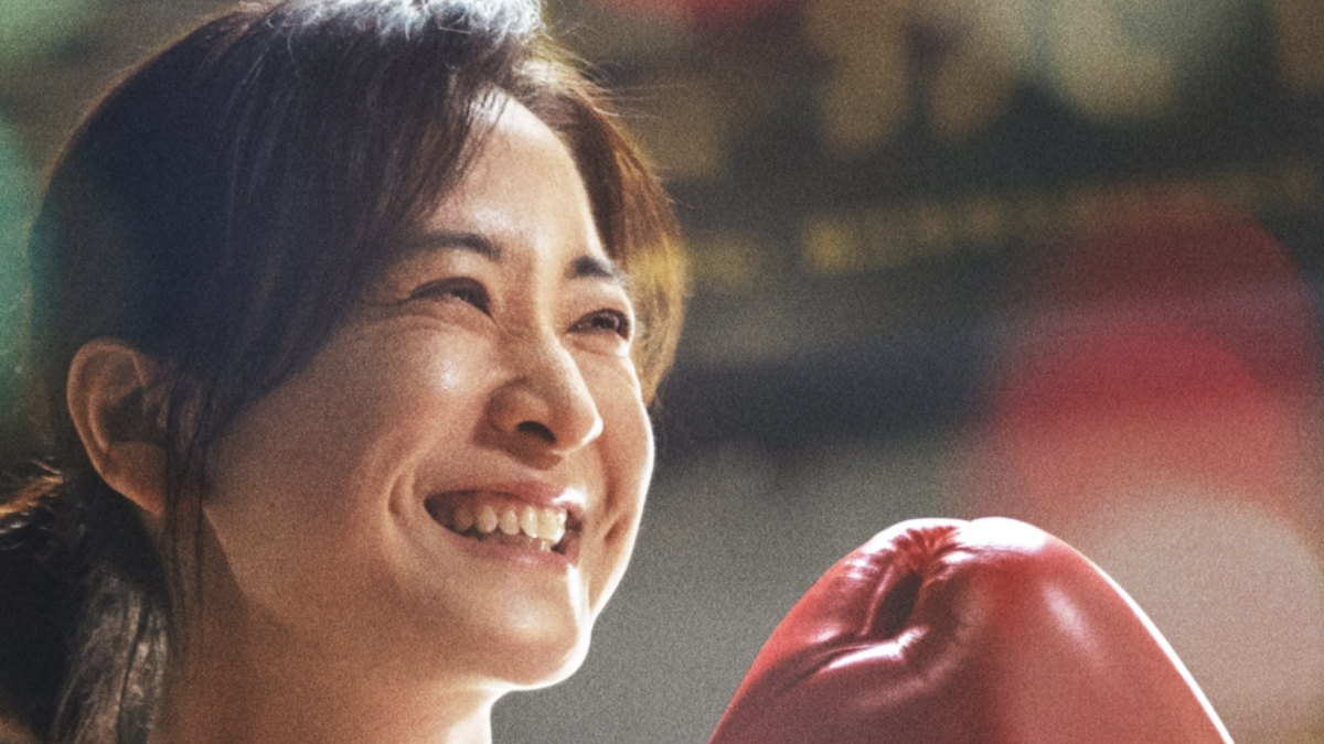 woman holding up boxing glove and smiling