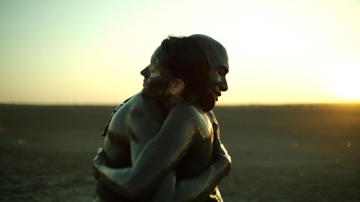 two people hugging in large field with sunsetting behind them