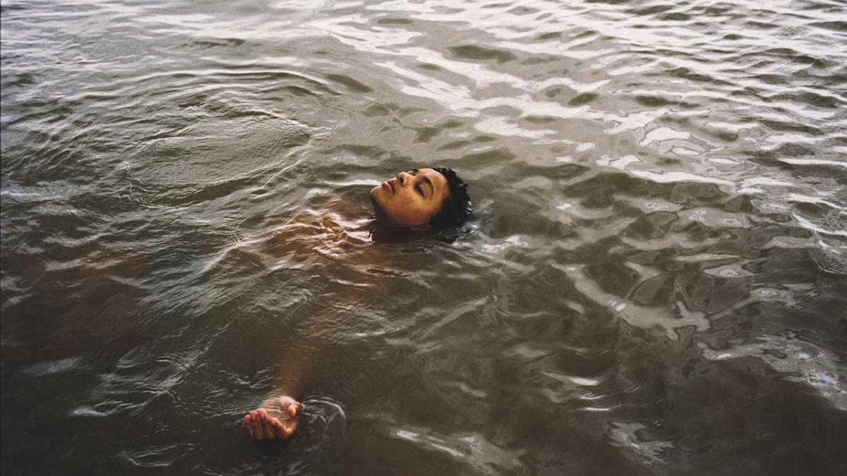 young boy floating on back in water with head poking up