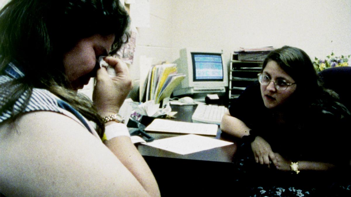 two woman seated in office and one woman crying