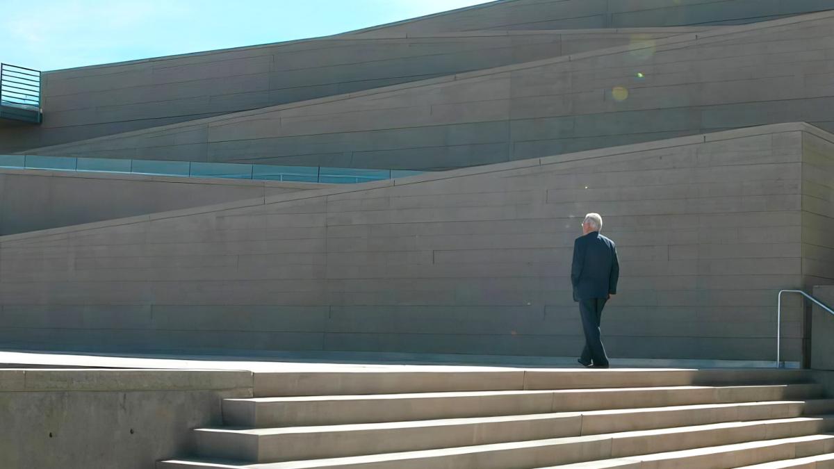 man in suit walking up steps in front of large building