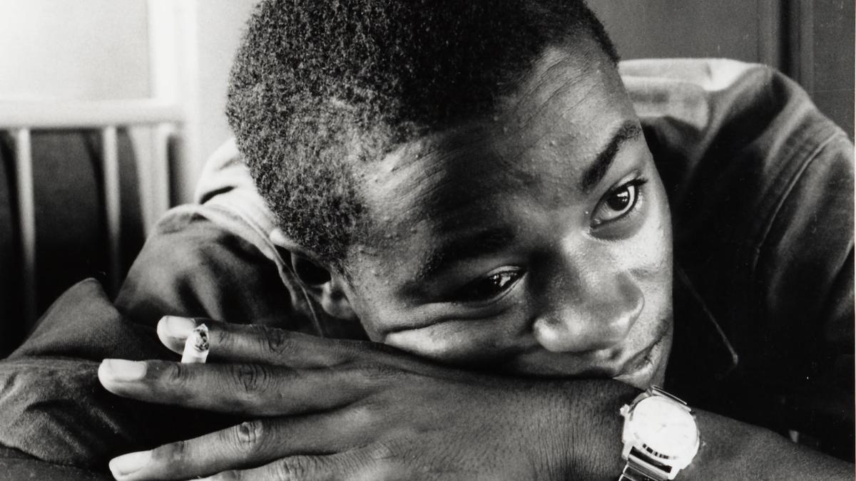 Black Man resting head on folded hands looking off in distance