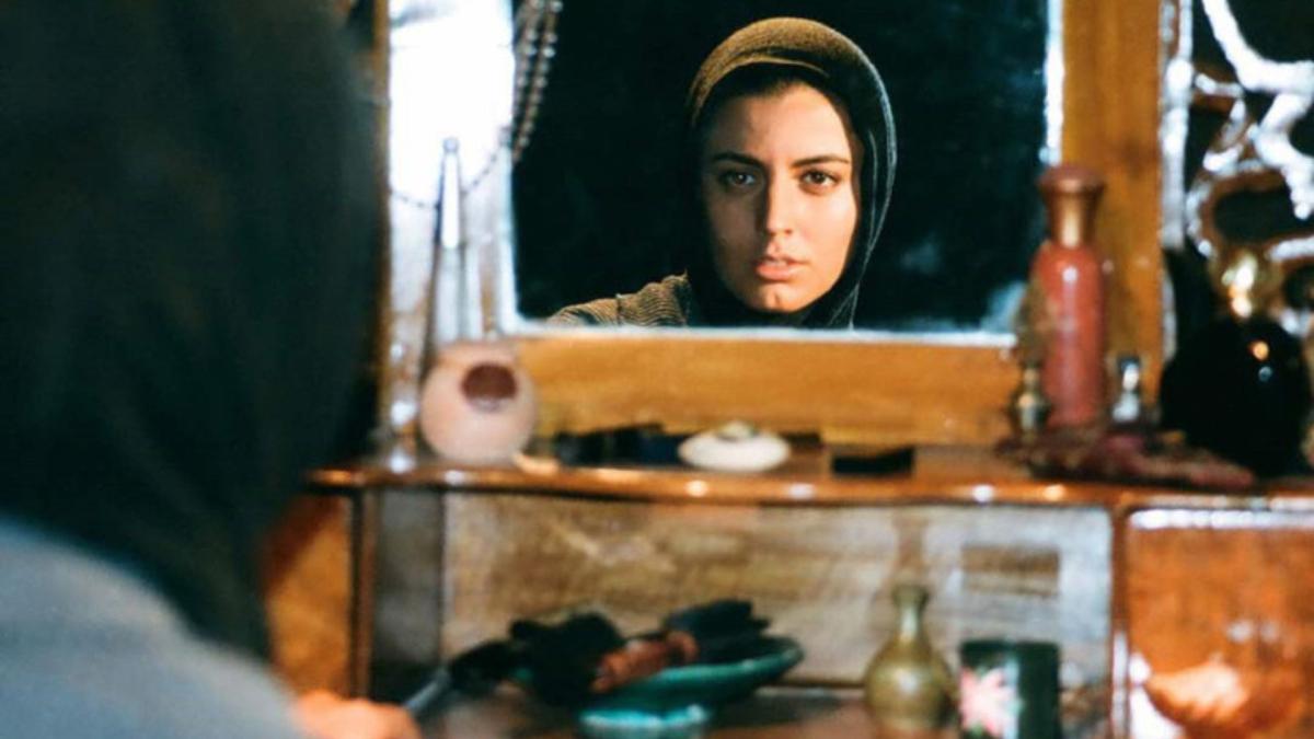 woman in hijab in front of sewing machine and looking into mirror