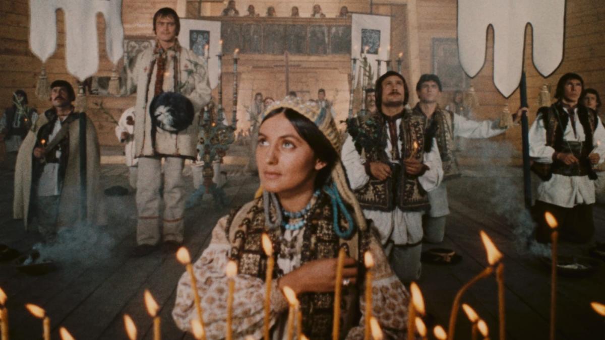 woman in traditional garb standing in front of candles with people arranged behind her