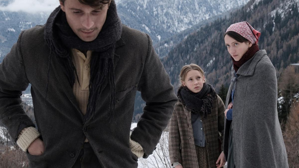 man, woman, and child standing on snowy mountaintop