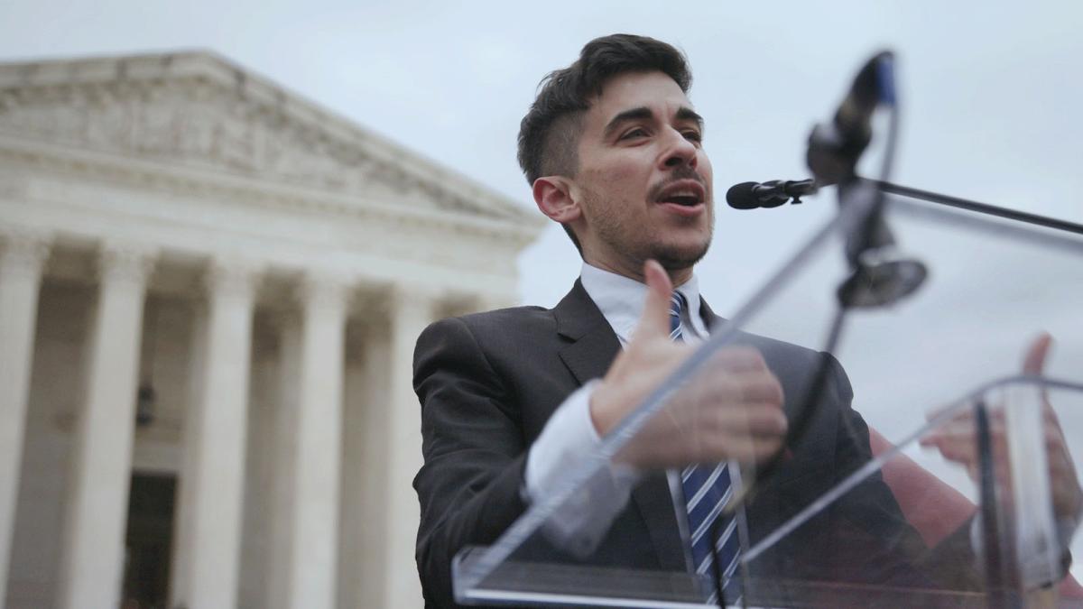 HEIGHTENED SCRUTINY, 2025, person in suit and tie speaking at podium in front of capitol building