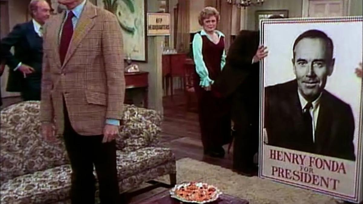 HENRY FONDA FOR PRESIDENT, 2024, men in suits standing in living room with large poster of Henry Fonda