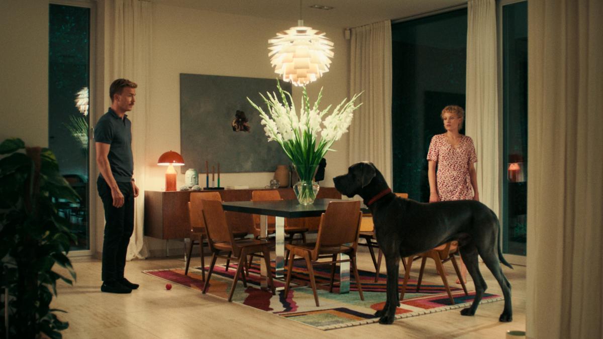 PEACOCK, 2024, couple standing in dining room with large black dog nearby