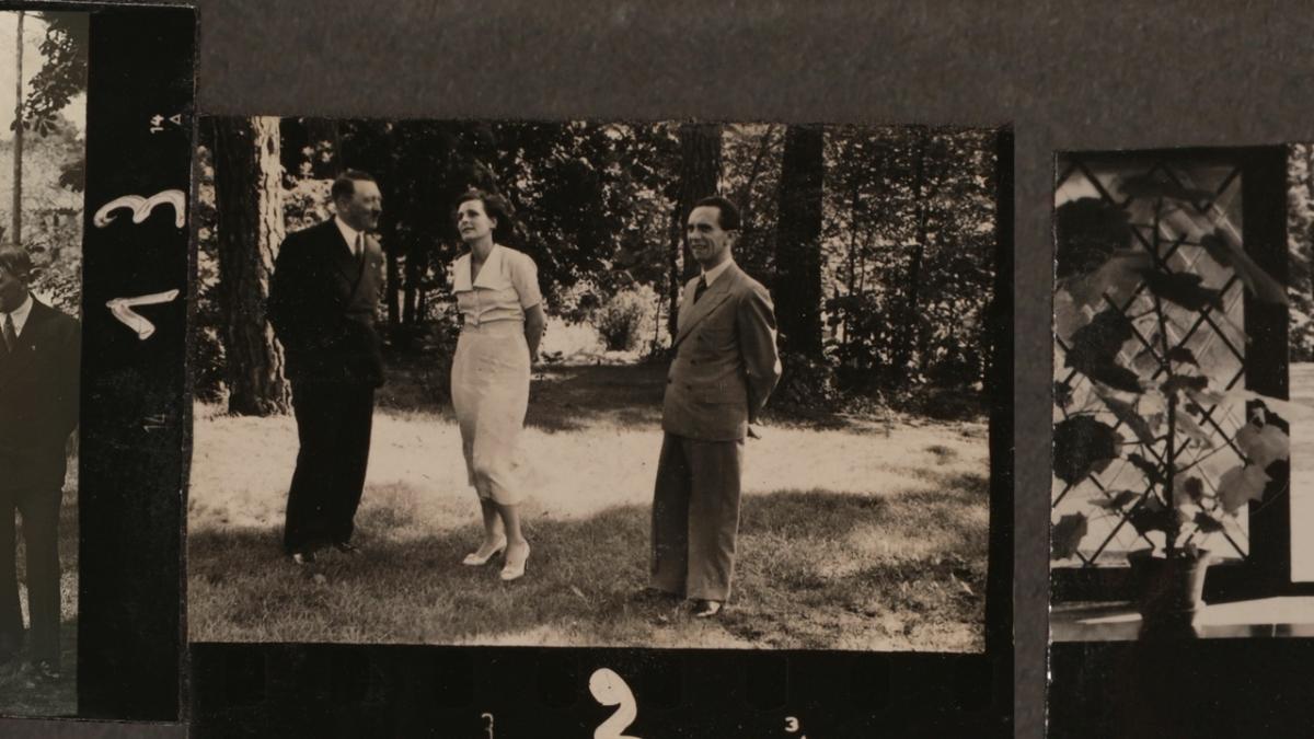 RIEFENSTAHL, 2024, black and white photo of woman standing near Hitler and Nazis in field of grass