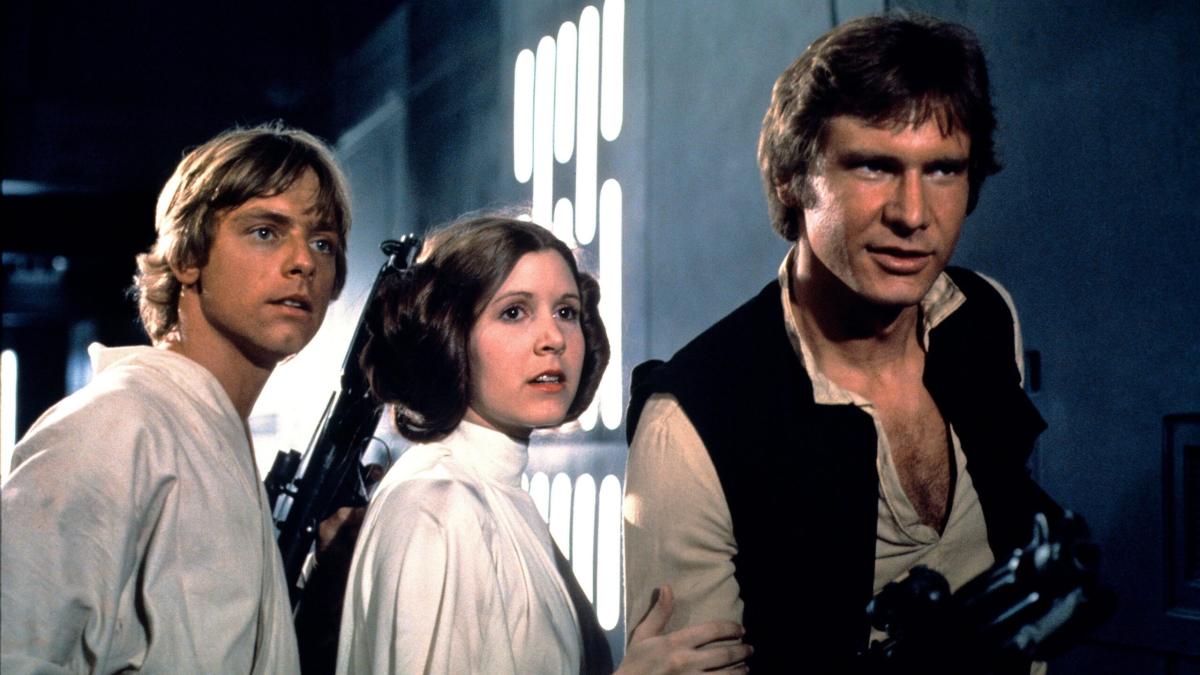 STAR WARS: EPISODE IV - A NEW HOPE, 1977, man in white shirt standing next to woman in white dress and man in brown vest looking ahead down hallway
