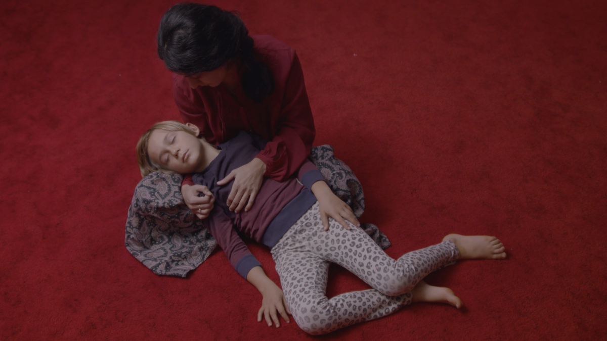 MY LIFE IS WIND, 2024, aerial shot of woman holding young boy in her arms on red carpet