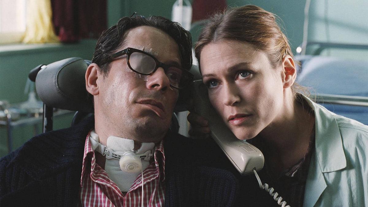 THE DIVING BELL AND THE BUTTERFLY, 2007, disabled man with glasses and woman in green coat talking on the phone with heads leaning close together