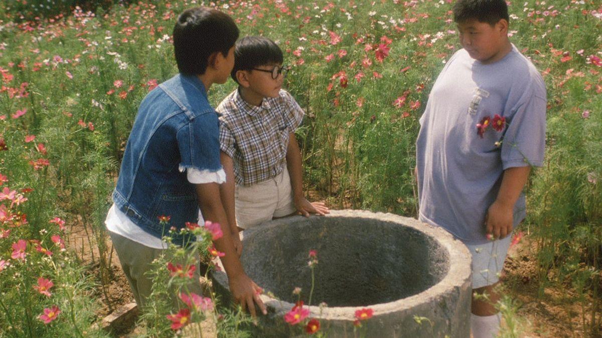 THE FRIENDS, 1994, three boys outside in grassy field positioned around large concrete hole