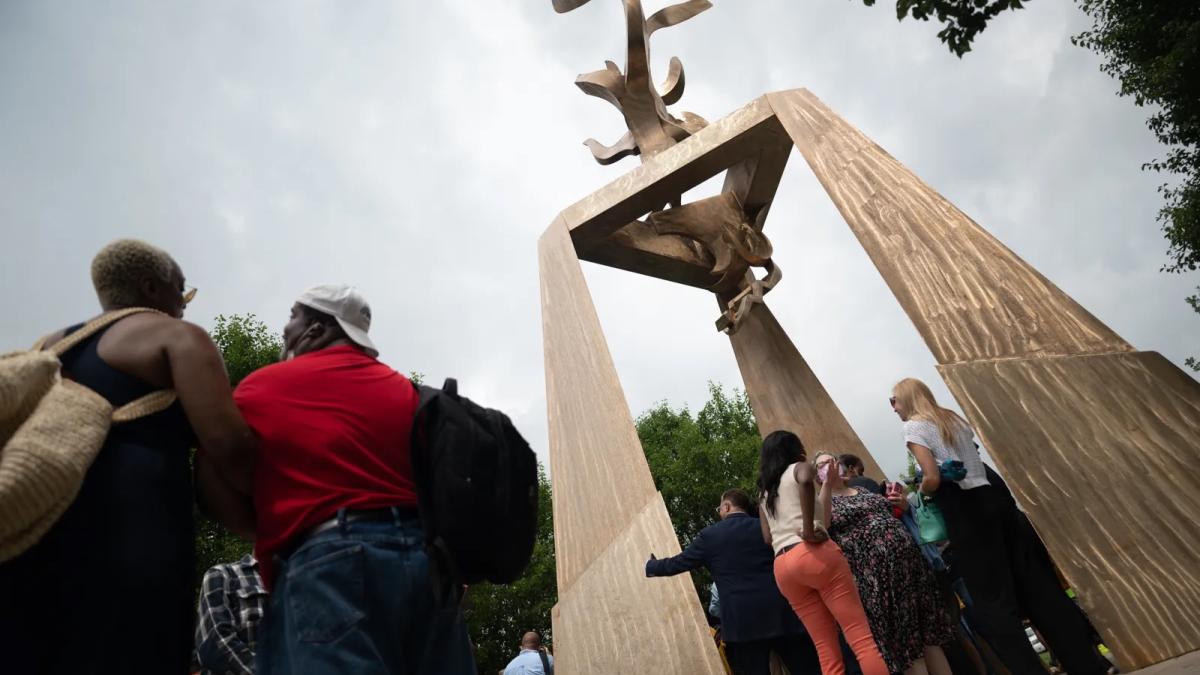 THE LIGHT OF TRUTH: RICHARD HUNT'S MONUMENT TO IDA B. WELLS, 2024, worms-eye view of people standing near tall public sculpture