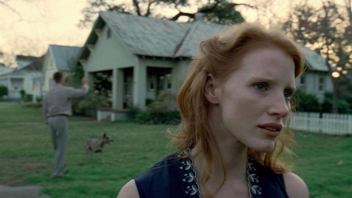 THE TREE OF LIFE, 2011, woman standing outside in yard looking into distance with children playing in background