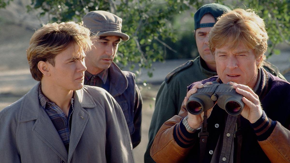 SNEAKERS, 1992, four men in fall clothing standing with one looking through binoculars 