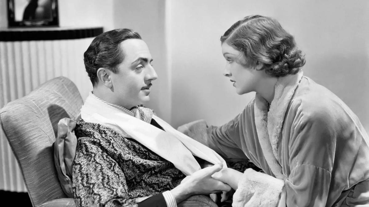 man in robe sitting on chair with woman in robe leaning over him holding hands