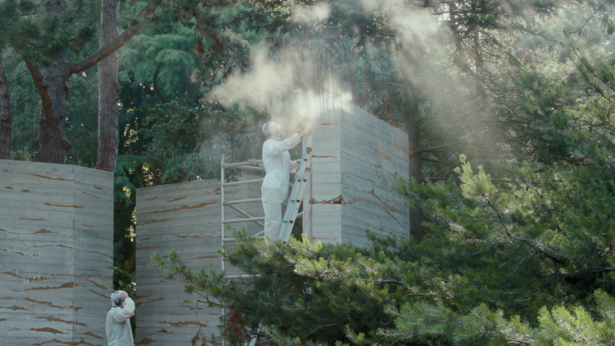 AT THE GARDEN'S PACE, 2024, two people in protective white suits and masks standing on ladder working on tall walls