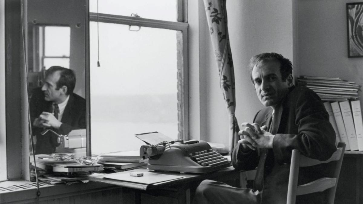 ELIE WIESEL: SOUL ON FIRE, 2024, black and white still of man seated at desk in front of window turning around 