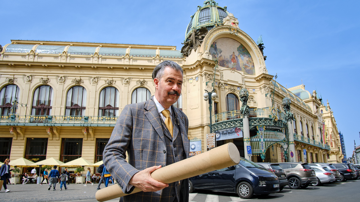 IDENTITY: A CZECH GRAPHIC DESIGN LOVE STORY, 2024, man holding tube of papers in front of large building on the street