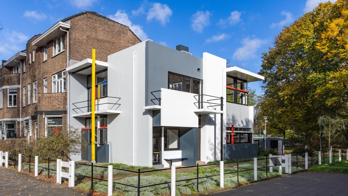 LIVING IN A PIECE OF FURNITURE: GERRIT RIETVELD’S HOUSES, 2024, exterior view of colorful house with yard