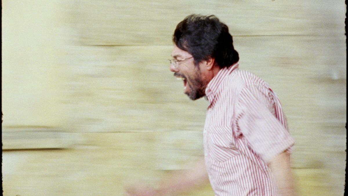 A POET, 2025, profile shot of man in pink button down shirt running down the street with mouth open