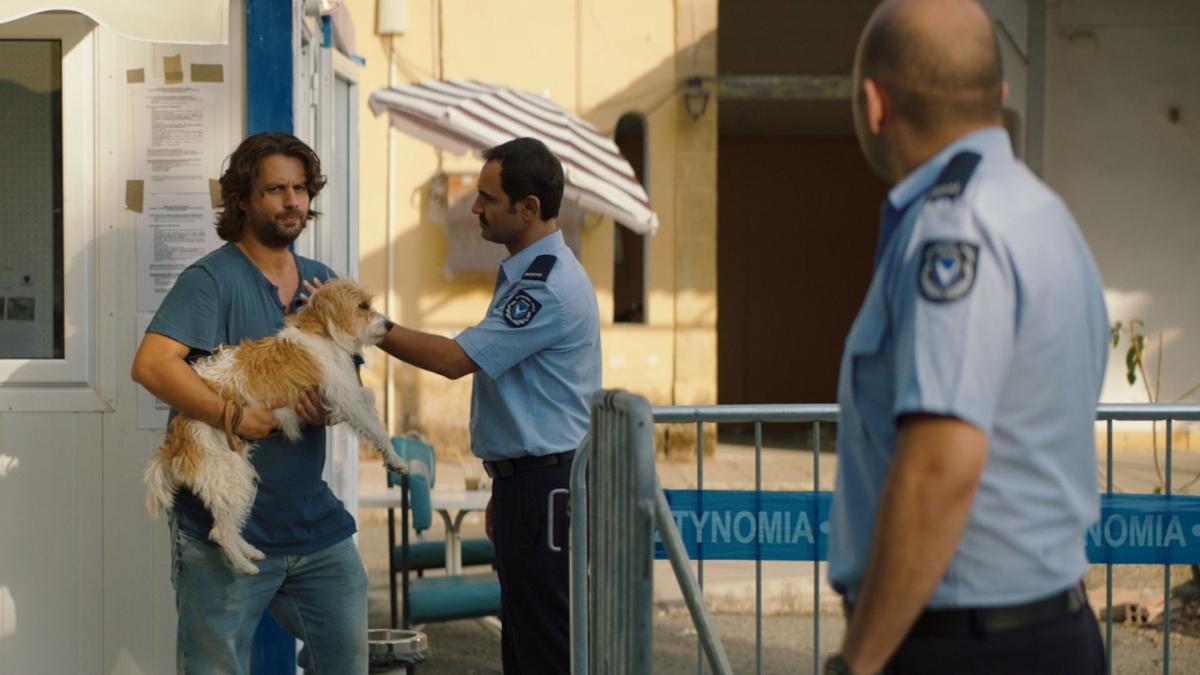 SMUGGLING HENDRIX, 2018, man holding small dog with police officers investigating