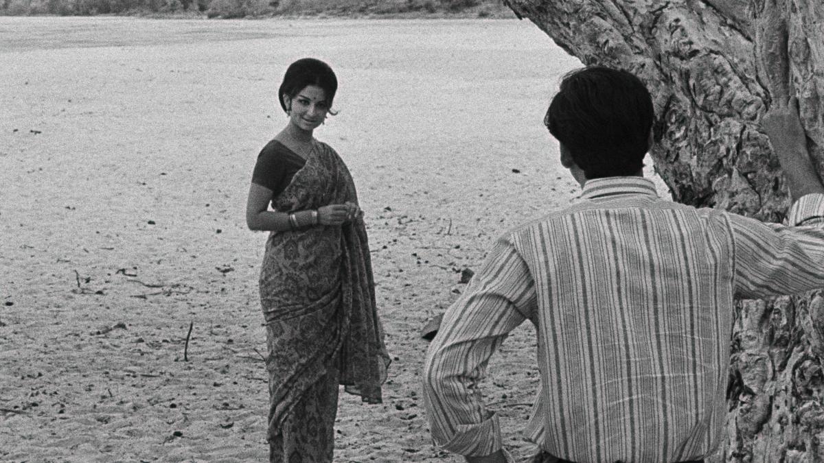 DAYS AND NIGHTS IN THE FOREST, 1970, Satyajit Ray, black and white image of women in sari looking towards man who is leaning against tree