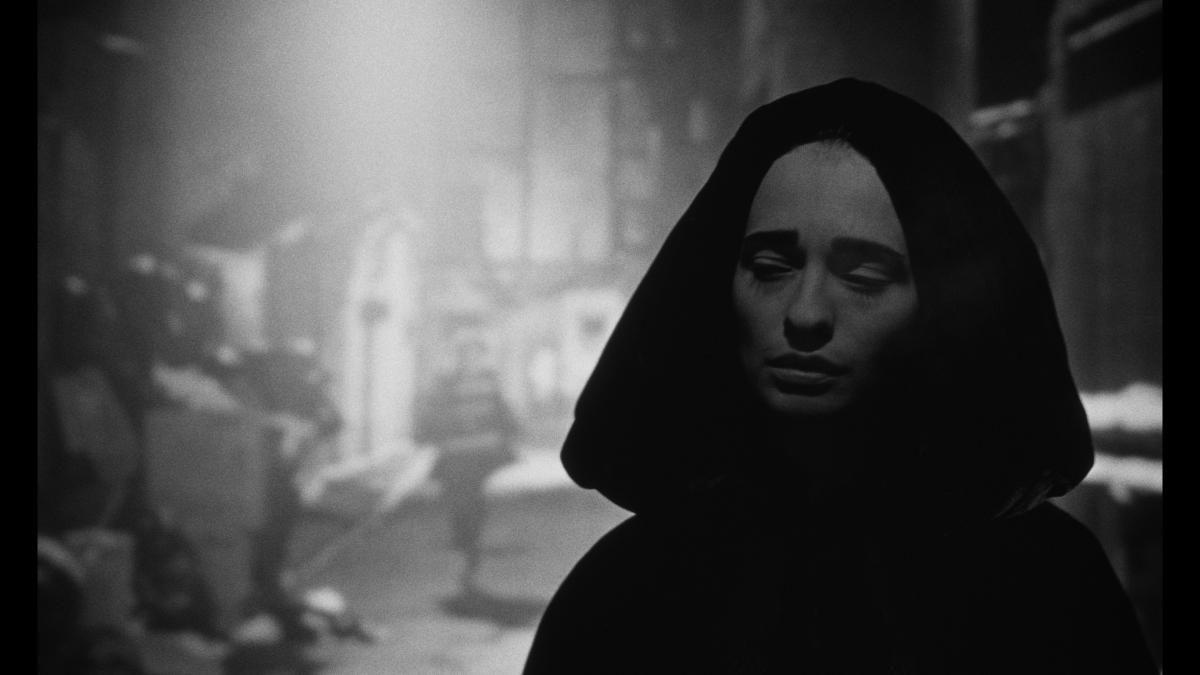 NADJA, 1994, black and white still of woman in a black hooded robe with light behind her