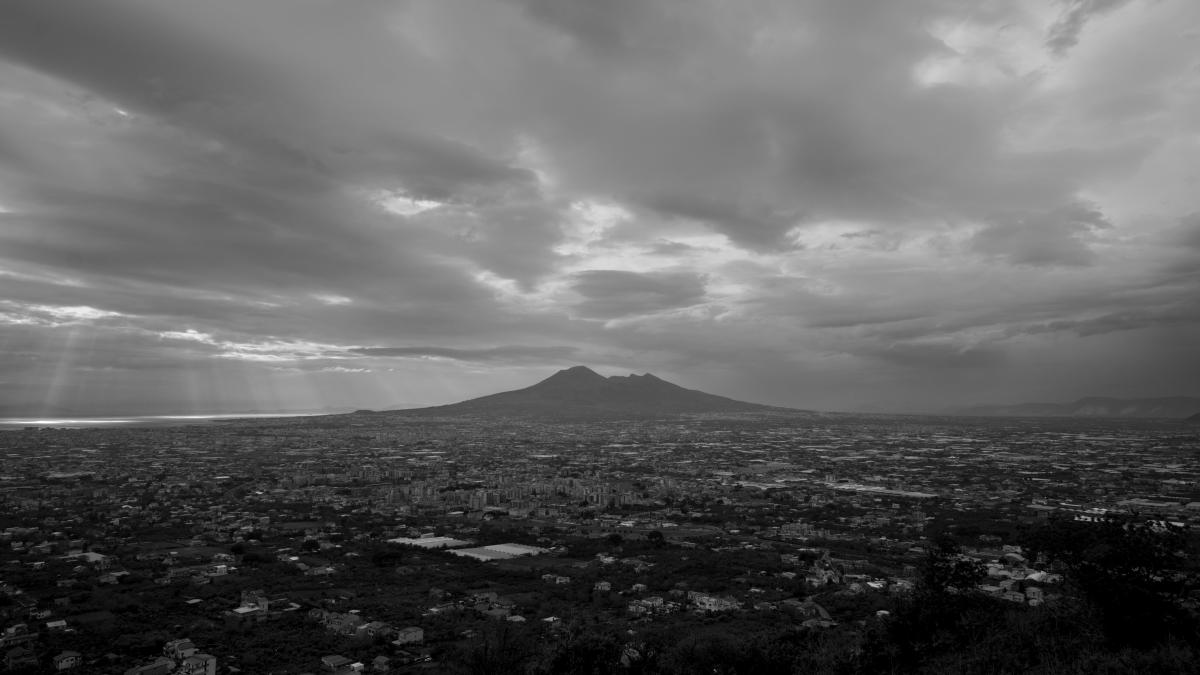 POMPEI: BELOW THE CLOUDS, 2025, black and white image of pompei in distance