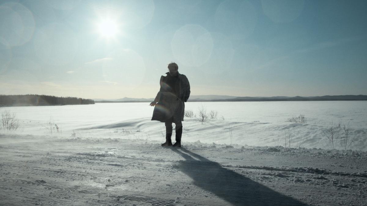 MR. NOBODY AGAINST PUTIN, 2025, silhouette of man standing in snowy field with bright sun behind him