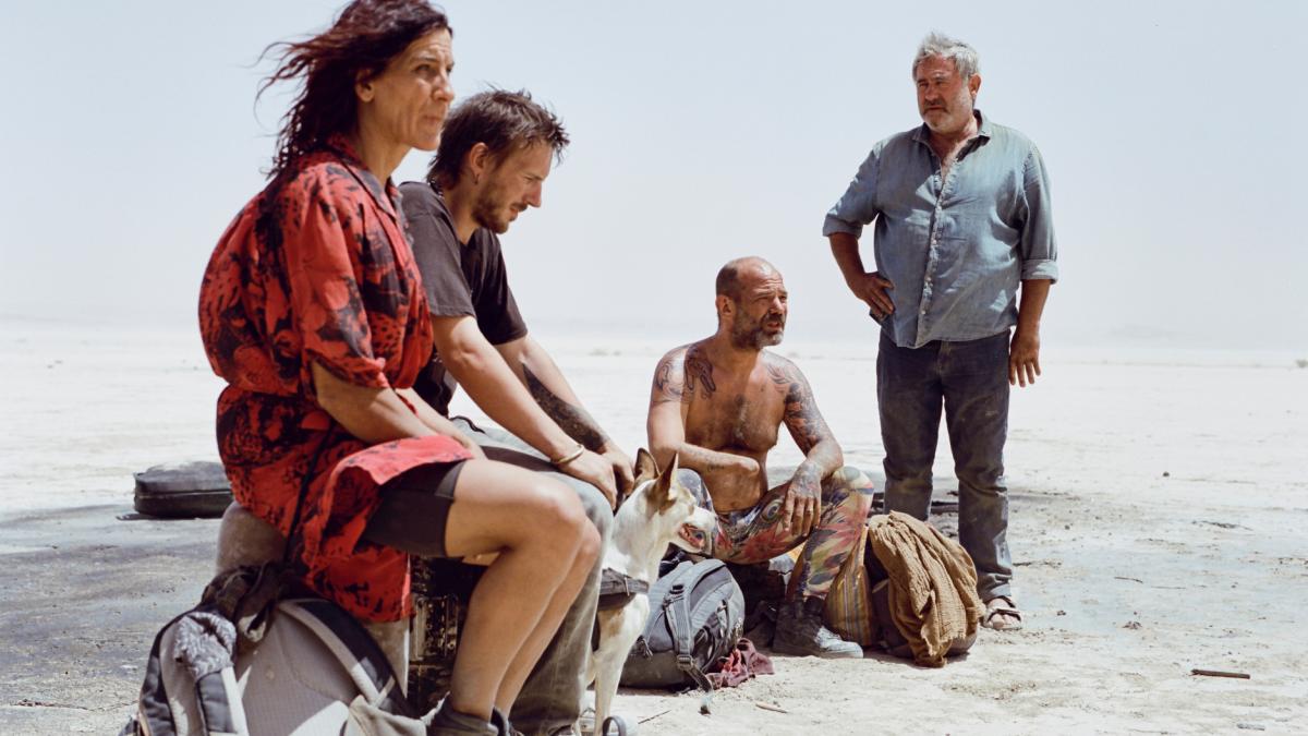 SIRAT, 2025, group of four people in semi circle in desert looking out into distance