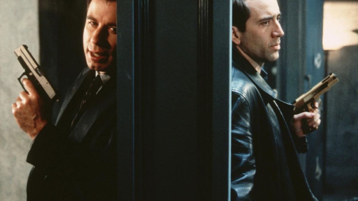 FACE/OFF, 1997, two men holding guns in leather jackets in split screen back to back