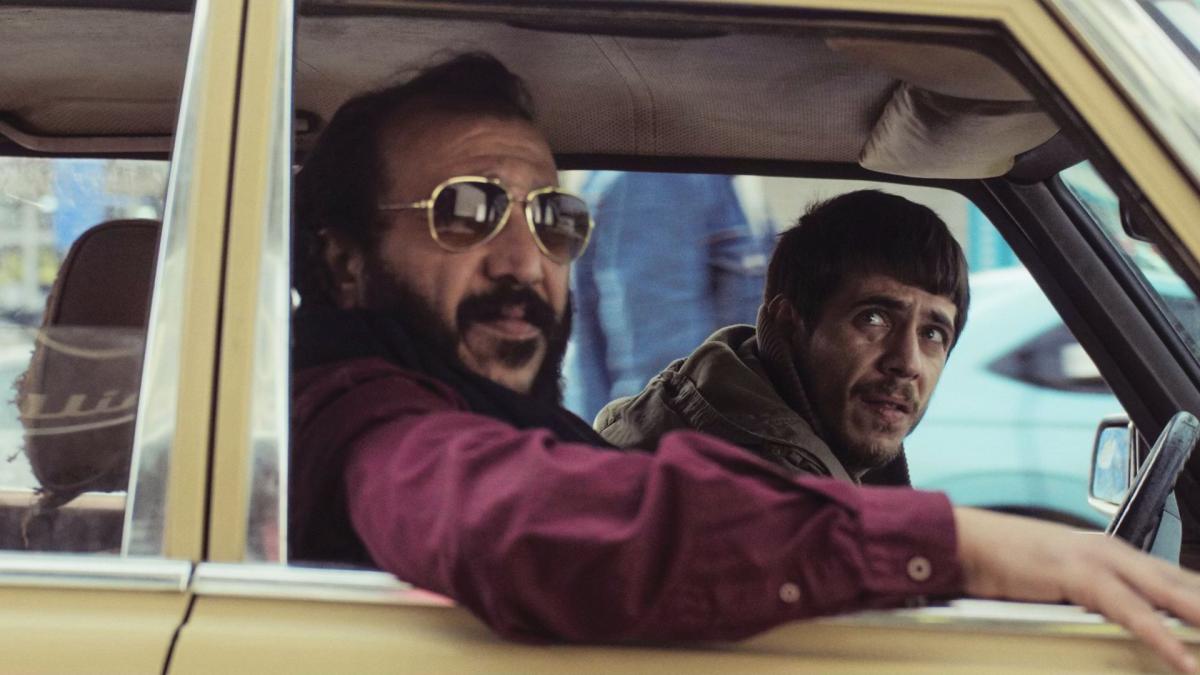 ONCE UPON A TIME IN GAZA, 2025, man in passenger seat of vehicle wearing sunglasses while he and driver look out his window