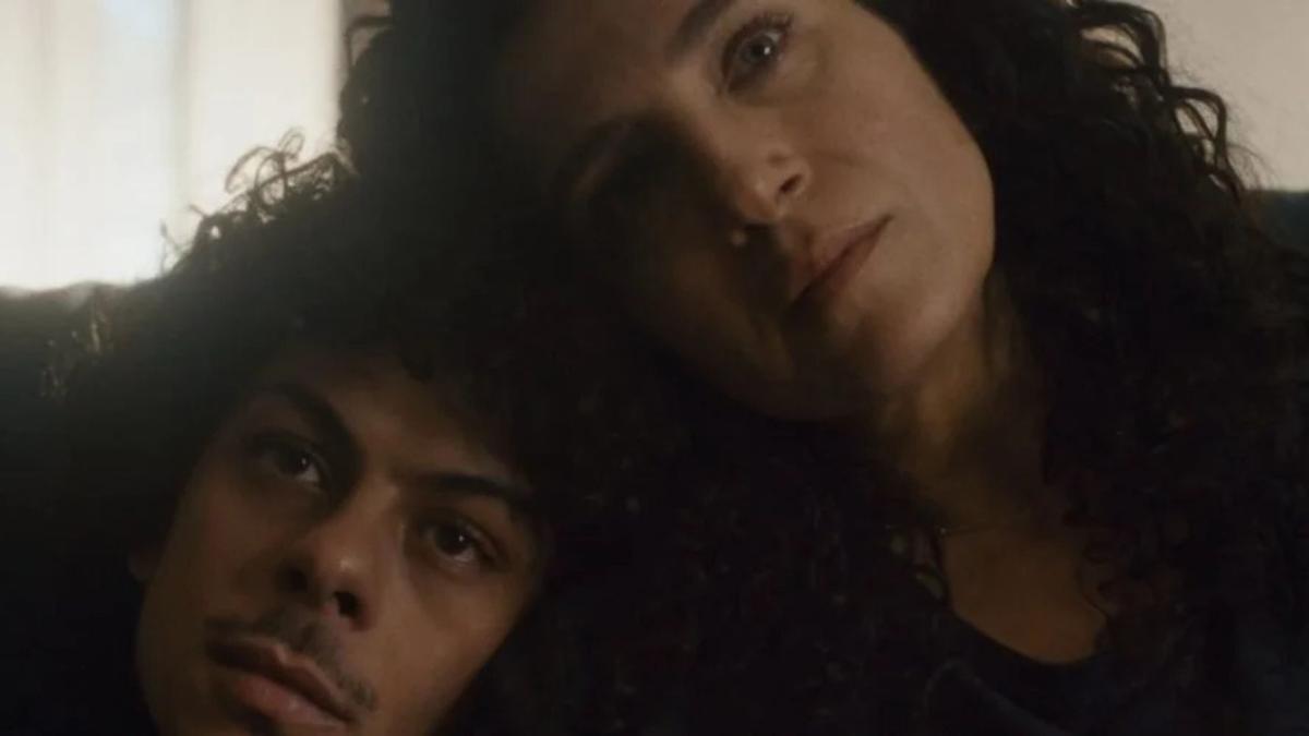 SINK, 2025, woman and boy sitting on sofa with heads resting on each other