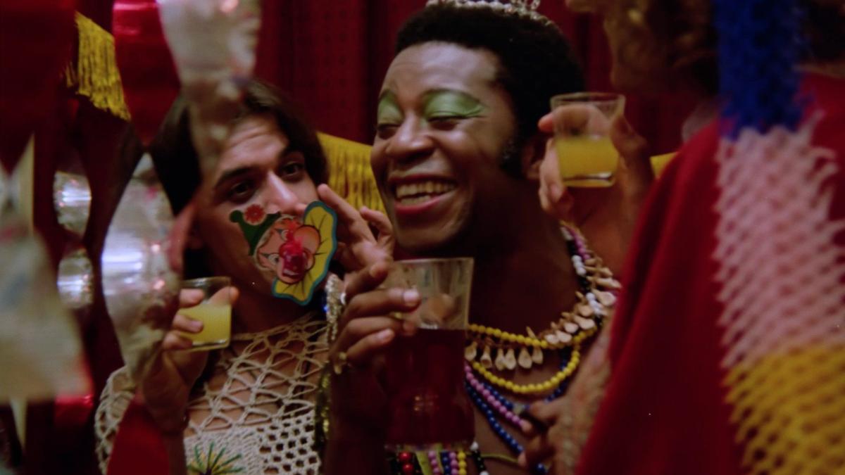 THE DEVIL QUEEN, 1974, Black man wearing tiara, green eyeshadow, colorful beads in vibrant colorful party