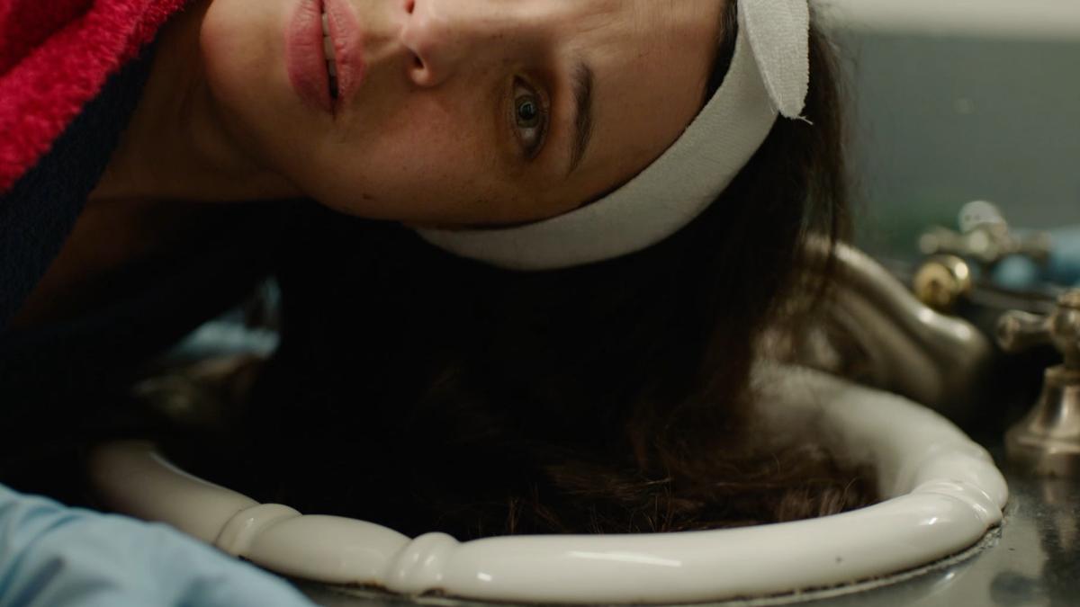 THE CURRENTS, 2026, woman wearing white headband leaning head sideways into sink