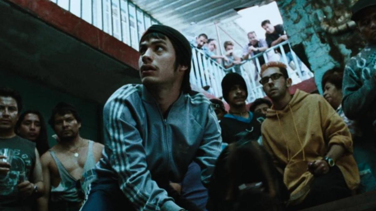 AMORES PERROS, 2000, man on ground holding dog with group of men standing behind him