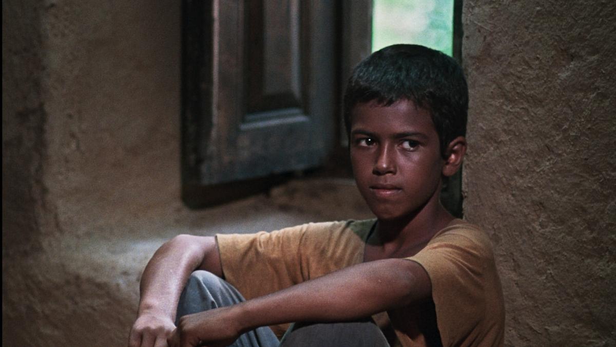BASHU, THE LITTLE STRANGER, 1985, young boy in yellow t-shirt sitting on ground with arms resting on knees