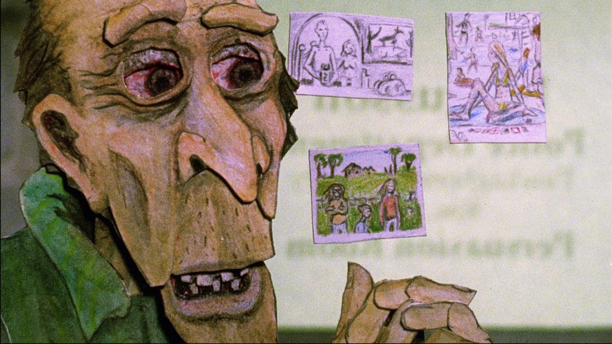 CONSUMING SPIRITS, 2012, animated man with bloodshot eyes with hands folded and three handmade drawings hanging up on wall behind him