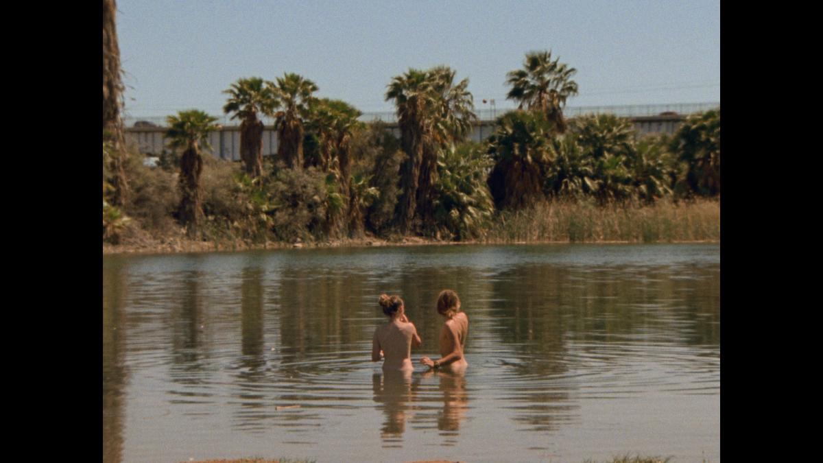 SUMMER TOUR, 2025, two people standing nude in a lake looking out into trees